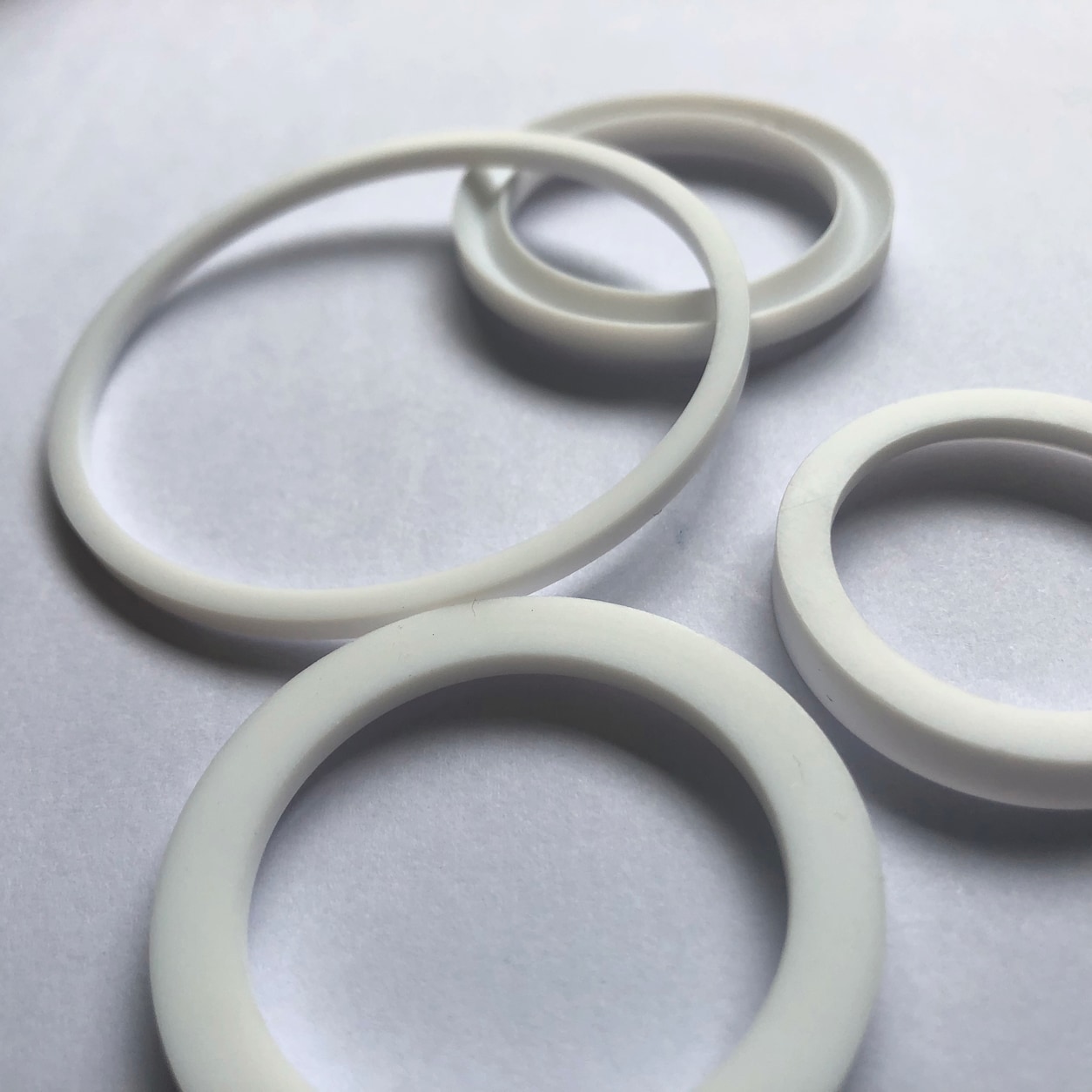 White solid PTFE O-rings in several sizes on a light background